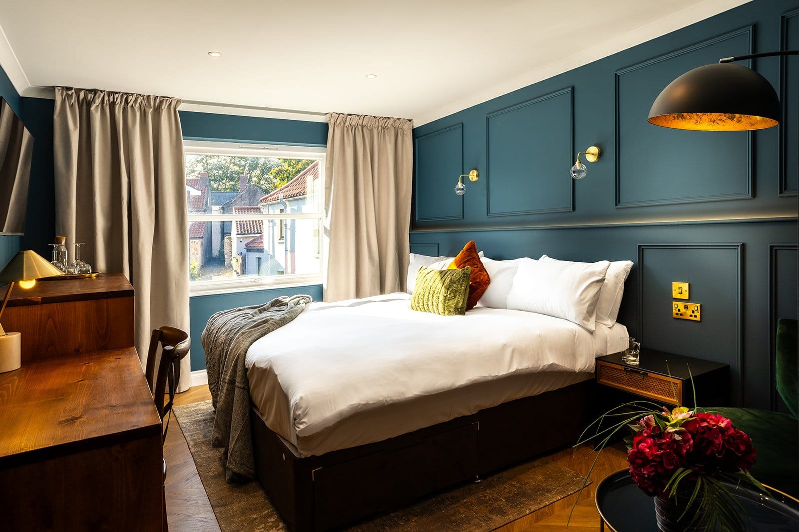 A cozy bedroom featuring blue walls and a neatly made bed